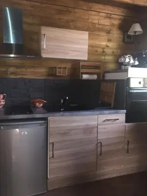 a kitchen with wooden cabinets and a stove top oven at Gîtes les Chalets Vezzani Spa in Vezzani