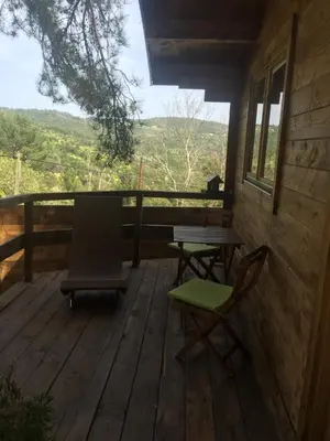 a porch with two chairs and a table and a view at Gîtes les Chalets Vezzani Spa in Vezzani