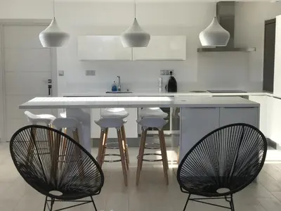 a kitchen with a white counter and bar stools at Sweet Holiday in Porto-Vecchio