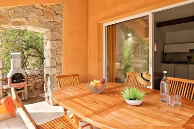 a wooden table with a bowl of fruit on a patio at Villas Abbartello in Olmeto