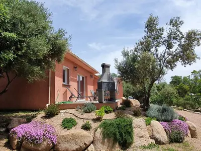 a house with a fireplace in front of a garden at Mini-villas Célia à BONIFACIO in Bonifacio