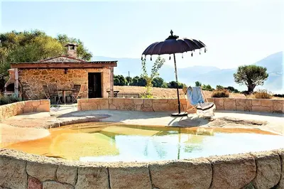 an umbrella and a chair in a pool of water at BERGERIE PARADISU, Domaine de l Ogliastru in Olmeto