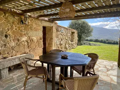 a table and chairs on a patio with a stone wall at BERGERIE PARADISU, Domaine de l Ogliastru in Olmeto