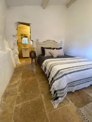 a bedroom with a bed and a stone floor at BERGERIE A Murta, Domaine de l Ogliastru in Olmeto