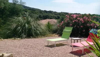 two chairs and a bench in a yard with flowers at Villa Les hauts de Benista in Porticcio