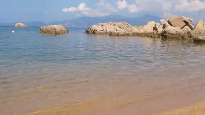 a beach with some rocks in the water at Villa Les hauts de Benista in Porticcio