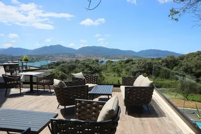 a patio with chairs and tables and a view of mountains at L'Hostellerie du Moulin des Oliviers in Olmeto