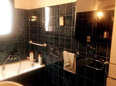a bathroom with a black tiled wall with a tub and a sink at Beau F4 petreto-Bicchisano in Petreto-Bicchisano