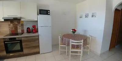a kitchen with a table and a white refrigerator at Vue mer Corse in Conca
