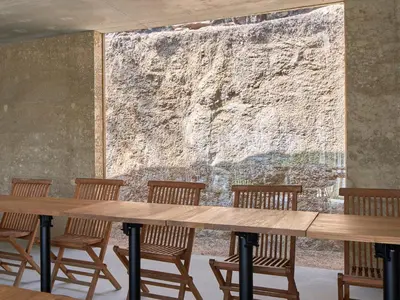a wooden table with chairs and a large wall at Vigna Maggiore in Olmeto