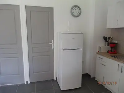 a white refrigerator in a kitchen with a clock on the wall at location vacances in Linguizzetta