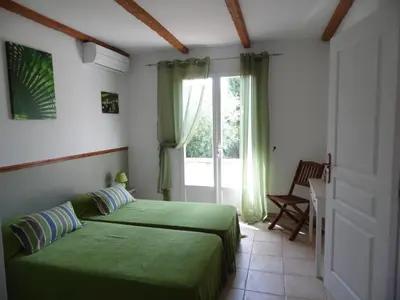 a bedroom with a green bed and a window at Locations Résidence Rocca Rossa Palombaggia classées 3 étoiles in Porto-Vecchio