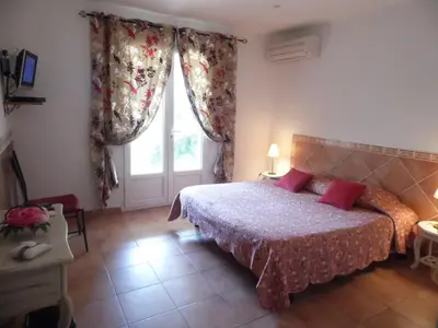 a bedroom with a bed with red pillows and a window at Locations Résidence Rocca Rossa Palombaggia classées 3 étoiles in Porto-Vecchio
