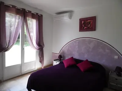 a bedroom with a purple bed and a large window at Locations Résidence Rocca Rossa Palombaggia classées 3 étoiles in Porto-Vecchio