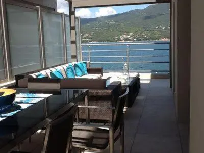 a balcony with a couch and a table and chairs at Plage Propriano 4 étoiles in Propriano
