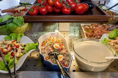 a table topped with plates of food and tomatoes at Hotel Club Marina Viva in Porticcio