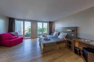 a hotel room with a bed and a pink couch at Hotel Club Marina Viva in Porticcio