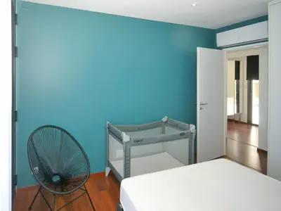 a bedroom with a blue wall with a bed and a fan at Sunset Villa with Bay View in Molini