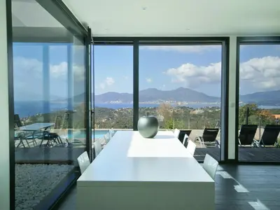 a white table and chairs in a room with windows at Sunset Villa with Bay View in Molini