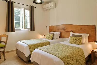 two beds in a hotel room with a window at Domaine de Bracciole in Corte