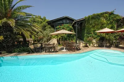a swimming pool with umbrellas and tables and chairs at Lodge de Charme A Cheda in Bonifacio