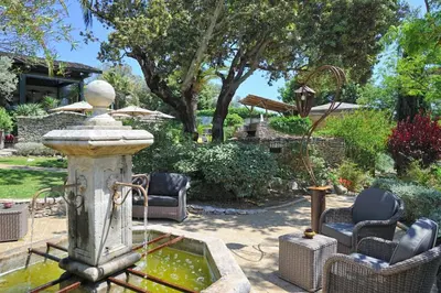 a fountain in the middle of a yard with chairs at Lodge de Charme A Cheda in Bonifacio