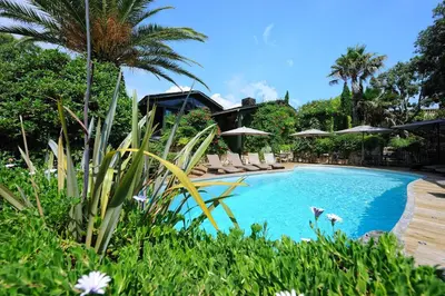 a swimming pool with chairs and umbrellas in a resort at Lodge de Charme A Cheda in Bonifacio