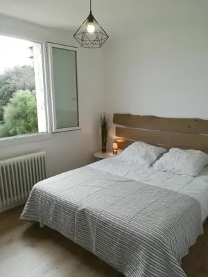 a bedroom with a large bed with a window at Appartement Lumineux Vue Panoramique in Ajaccio
