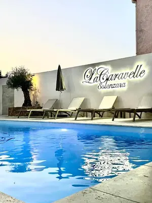 a swimming pool with chairs and a sign on a wall at Hôtel Restaurant La Caravelle in Sari Solenzara
