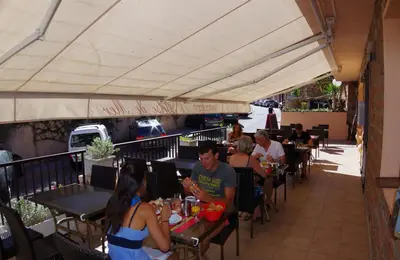 a group of people sitting at tables at a restaurant at Brise de Mer in Porto Ota