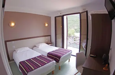 a hotel room with two beds and a balcony at Brise de Mer in Porto Ota