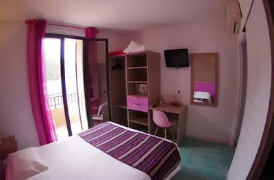 a bedroom with a bed and a desk and a mirror at Brise de Mer in Porto Ota
