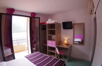 a bedroom with a bed and a desk with a mirror at Brise de Mer in Porto Ota