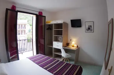 a bedroom with a bed and a desk and a window at Brise de Mer in Porto Ota