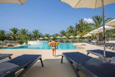 a man walking by the pool at a resort at Hôtel Campo Dell'oro in Ajaccio
