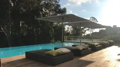 a patio with couches and an umbrella next to a pool at Hôtel et Résidence Costa Rossa in Porto Ota