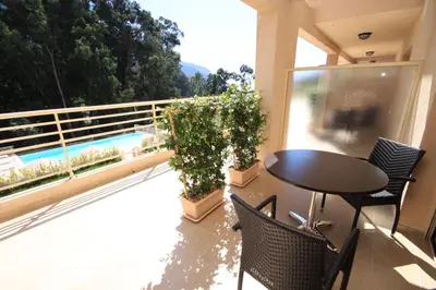 a balcony with a table and chairs and a pool at Hôtel et Résidence Costa Rossa in Porto Ota