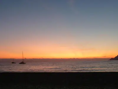 a sunset on the beach with boats in the water at Hôtel et Résidence Costa Rossa in Porto Ota