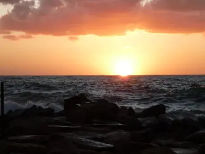 a sunset over the ocean with rocks at Hôtel et Résidence Costa Rossa in Porto Ota