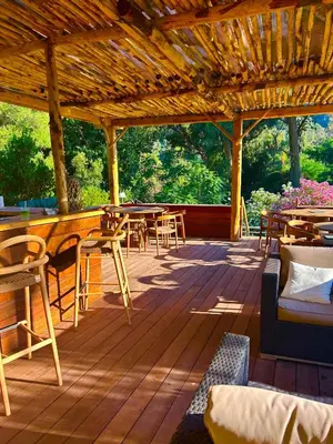a large wooden deck with tables and chairs at Hôtel et Résidence Costa Rossa in Porto Ota