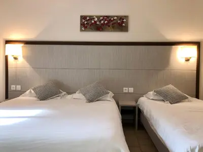 two beds in a hotel room with white sheets at Hotel et Résidence Cala di sole in Porto Ota
