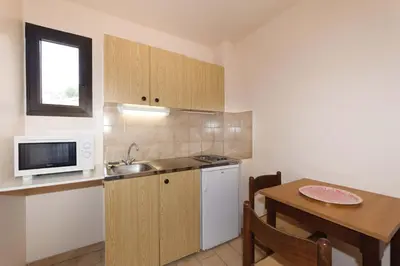 a small kitchen with a table and a microwave at Hotel et Résidence Cala di sole in Porto Ota