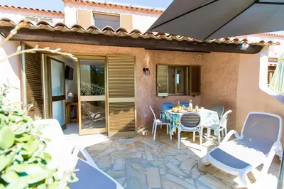 a patio with a table and chairs in front of a house at Résidence Stella di Mare in Sainte-Lucie de Porto-Vecchio