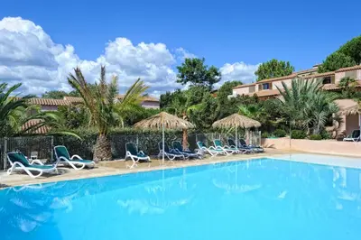 a swimming pool with chairs and umbrellas at Résidence Stella di Mare in Sainte-Lucie de Porto-Vecchio