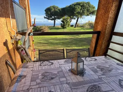 a table on a balcony with a view of a yard at Appartement n 79 Moriani plage in Santa-Lucia-di-Moriani