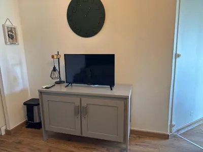 a tv on a wall with a clock on the wall at Appartement n 79 Moriani plage in Santa-Lucia-di-Moriani