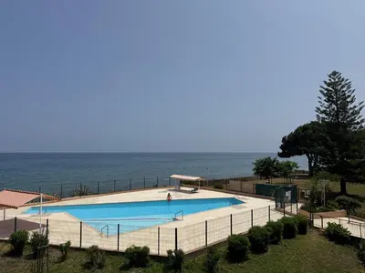 a swimming pool with the ocean in the background at Appartement n 79 Moriani plage in Santa-Lucia-di-Moriani
