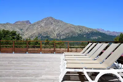 a row of lounge chairs on a deck with mountains at Castel de Vergio in Albertacce