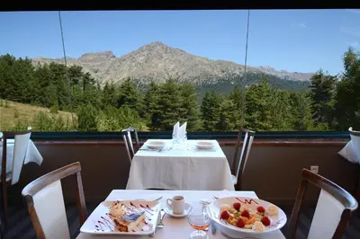 a table with two plates of food and a view of a mountain at Castel de Vergio in Albertacce