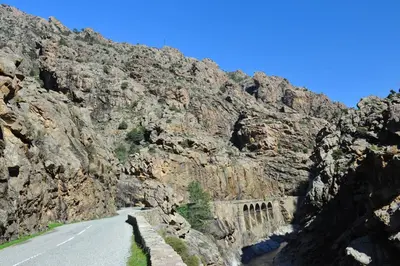 a road through a rocky mountain with a bridge at Castel de Vergio in Albertacce
